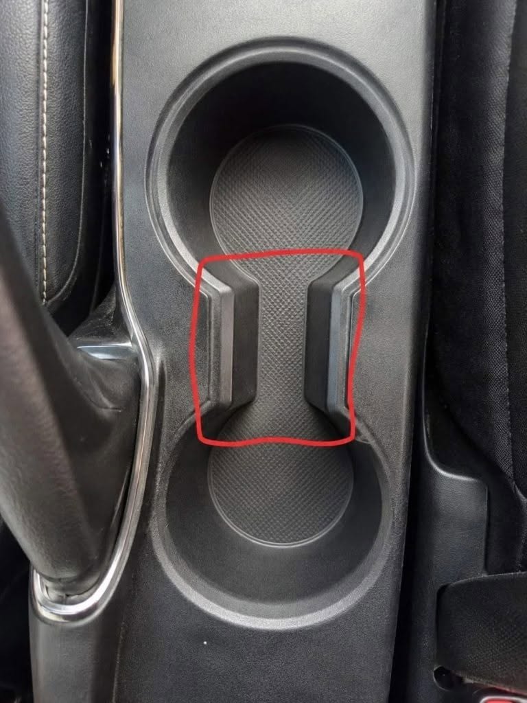 Aký je účel toho zvláštneho priestoru medzi držiakmi na poháre v aute?…